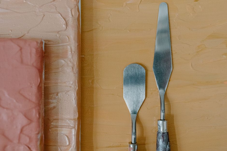 Close-up of palette knives and textured acrylic canvas, ideal for artistic projects.